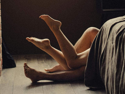 Couple in bed with intertwined legs. Discover science-backed techniques for lasting longer in bed, tailored for Filipino men, at andyou.ph.