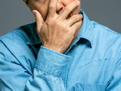 Man in denim shirt covering his mouth in concern. Learn about the best treatments for premature ejaculation in the Philippines at andyou.ph.